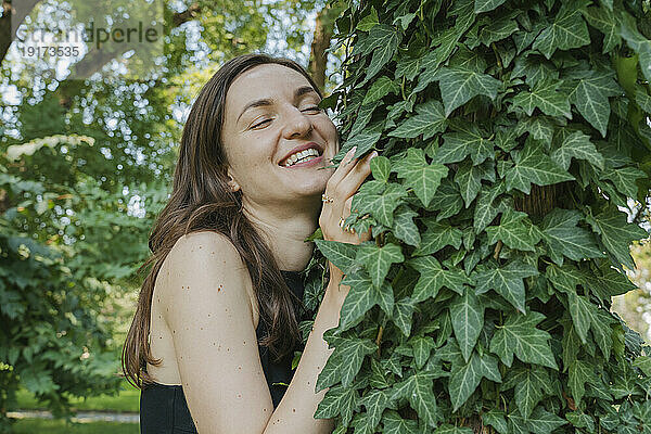 Glückliche Frau umarmt Baum im Garten