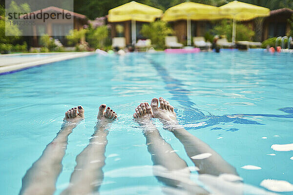 Beine einer Frau schwimmen im Pool des Resorts