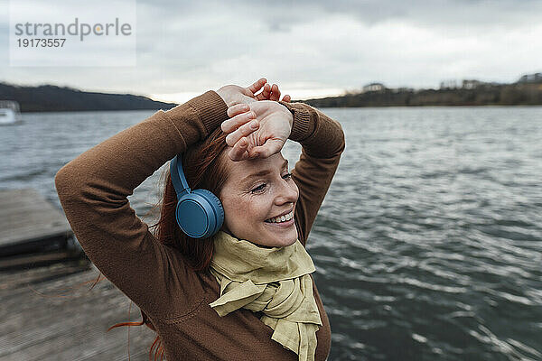 Lächelnde Frau  die am See Musik hört
