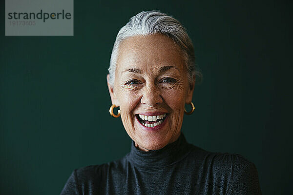 Mature woman laughing in front of wall