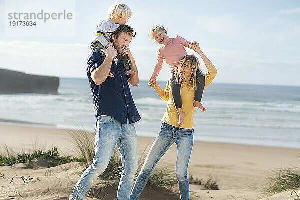Familie amüsiert sich an einem sonnigen Tag gemeinsam am Strand