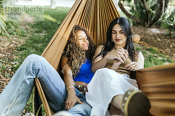 Smiling girlfriends spending leisure time in hammock