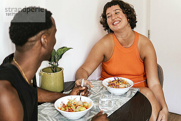 Glückliches Paar redet und isst Salat auf dem Esstisch