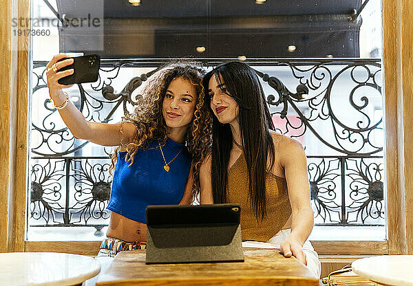Lächelnde Freundinnen machen Selfie mit dem Handy im Café