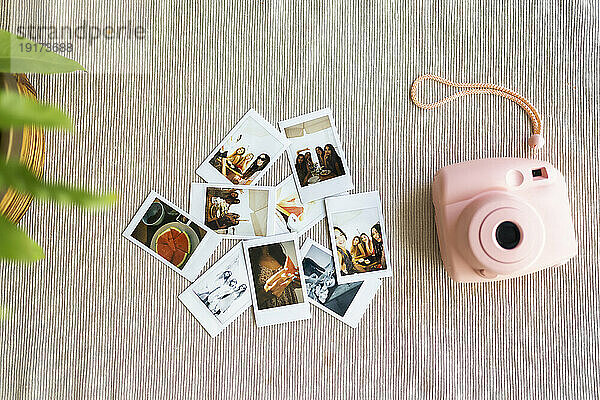 Pink instant camera next to photographs