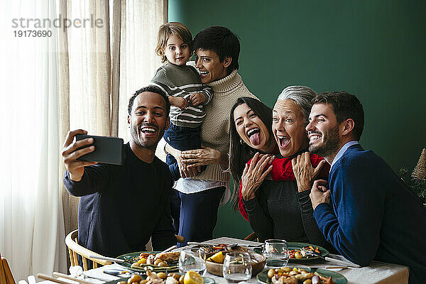 Glückliche gemischtrassige Familie  die an Weihnachten zu Hause ein Selfie über das Smartphone macht