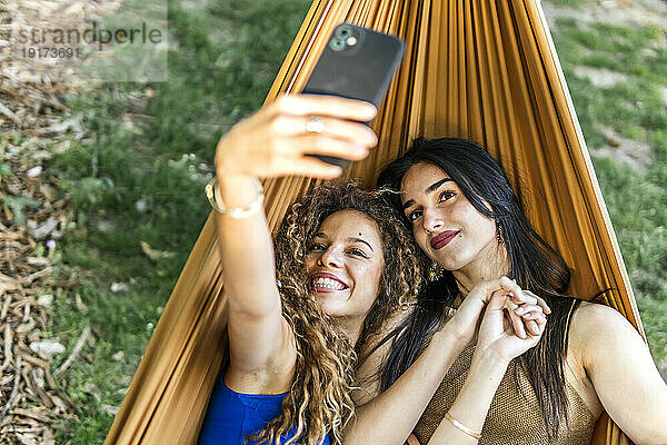 Lächelnde junge Freundinnen machen Selfie mit dem Handy in der Hängematte