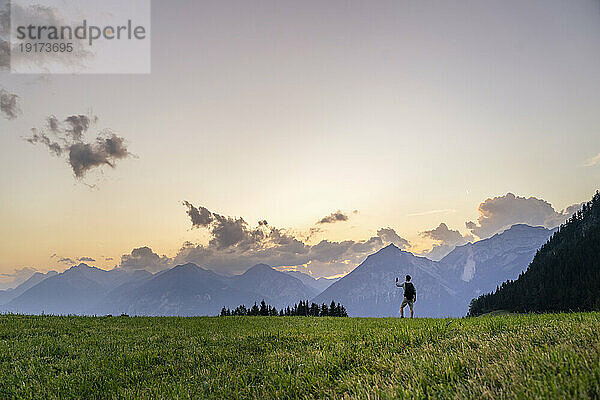 Man hiking in meadow by mountain range