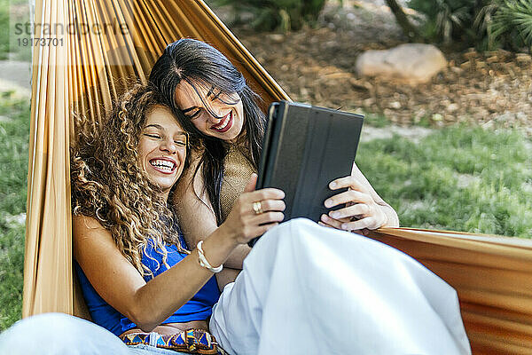 Glückliche junge Frauen nutzen Tablet-PC in der Hängematte
