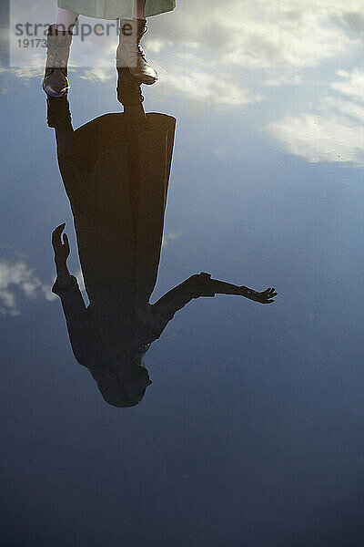 Reflection of woman in water puddle