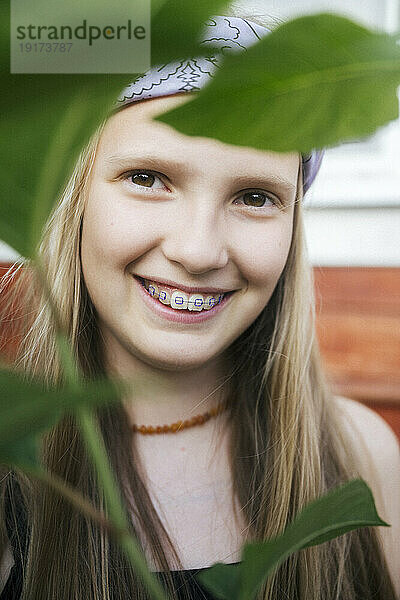 Lächelndes Mädchen mit Zahnspange in der Nähe von Blatt