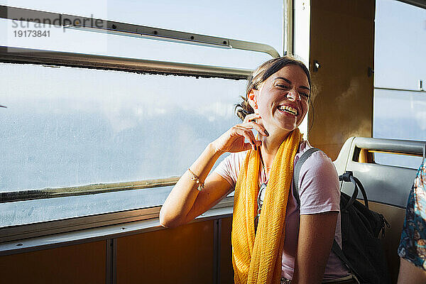 Glückliche Frau sitzt im Zug neben dem Fenster