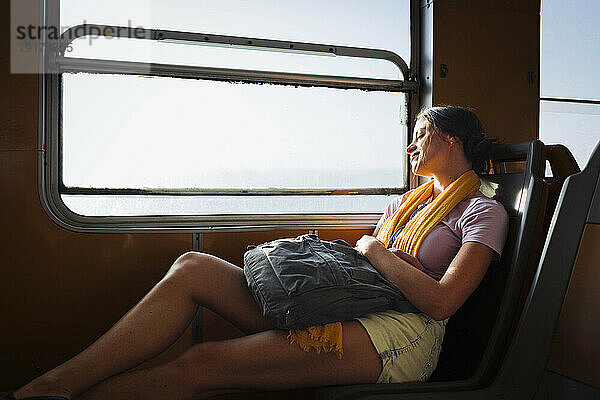 Junge Frau mit Rucksack entspannt sich im Zug