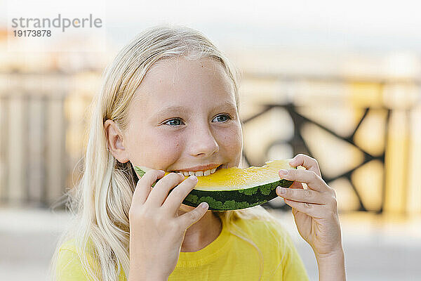 Lächelndes blondes Mädchen  das gelbe Wassermelone isst