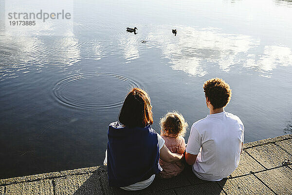 Familie schaut sich Enten an  die im See schwimmen