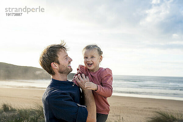 Glücklicher Vater und Tochter vor dem Meer an einem sonnigen Tag