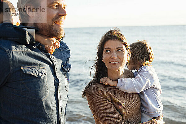 Mutter und Vater mit Kindern auf dem Seeweg am Strand im Urlaub
