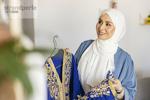 Glücklicher junger Modedesigner mit blauem Hochzeitskleid