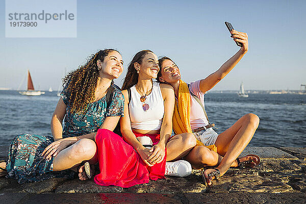 Glückliche Frau macht Selfie mit Freunden an der Promenade