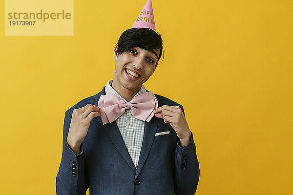 Cheerful man wearing bow tie and party hat on birthday