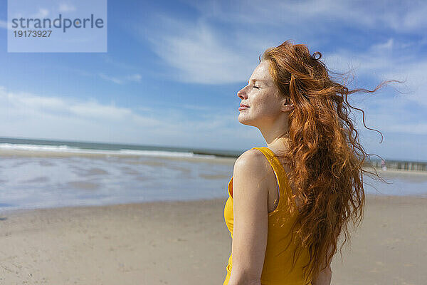Frau genießt im Urlaub den Wind am Strand