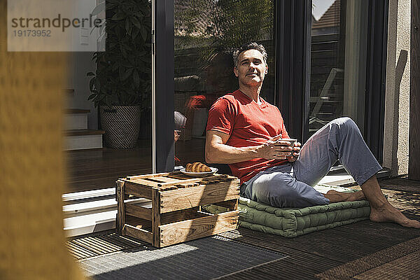 Man relaxing on balcony with mug in hand