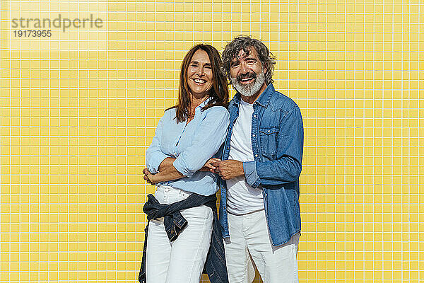 Fröhliche ältere Männer und Frauen tanzen vor der gelben Wand