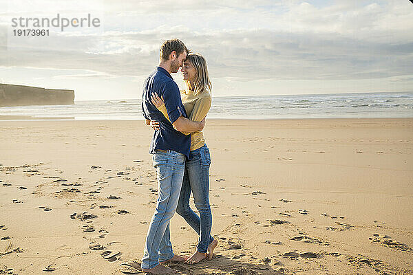 Glückliche Frau und Mann umarmen sich am Strand