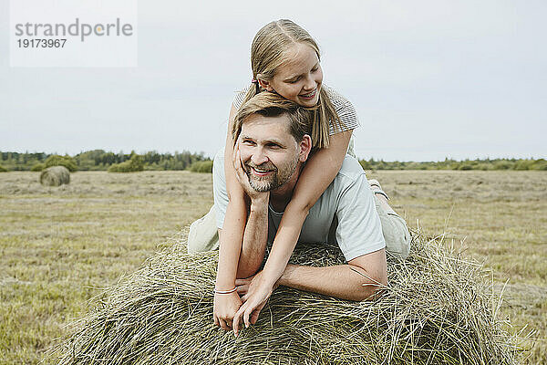 Glückliche Tochter und Vater liegen auf Heu im Feld