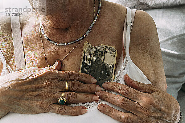 Senior woman holding old photograph on chest
