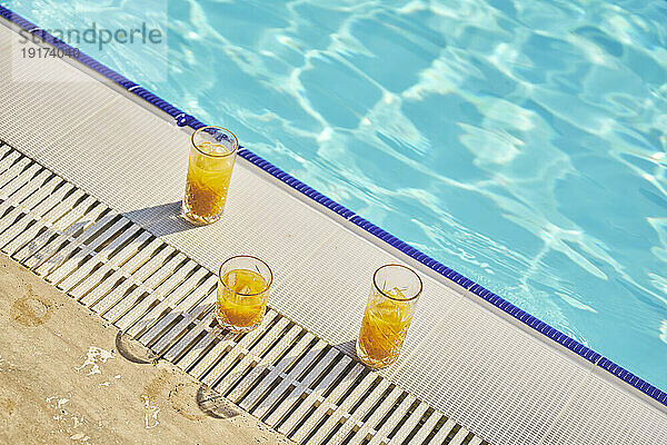 Gläser Orangensaft in der Nähe des Schwimmbades an einem sonnigen Tag