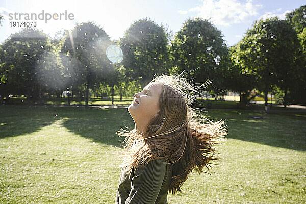 Cheerful blond girl enjoying in park on sunny day