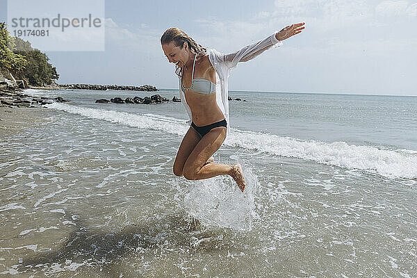 Glückliche Frau springt am Strand
