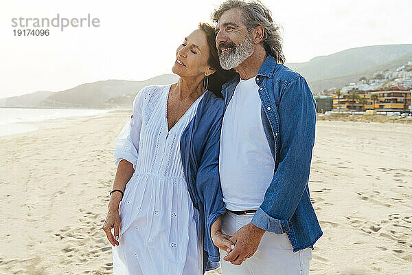 Lächelnder Mann und Frau stehen zusammen am Strand