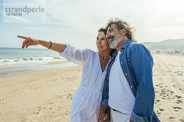 Lächelnde Frau gestikuliert mit Mann  der am Strand steht