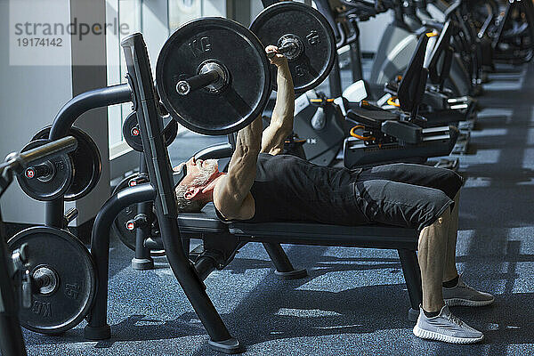 Reifer Mann macht Bankdrücken im Fitnessstudio