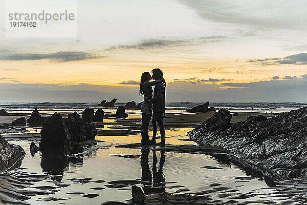 Paar küsst sich bei Sonnenuntergang am Strand