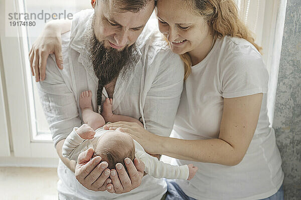 Happy parents carrying newborn daughter at home