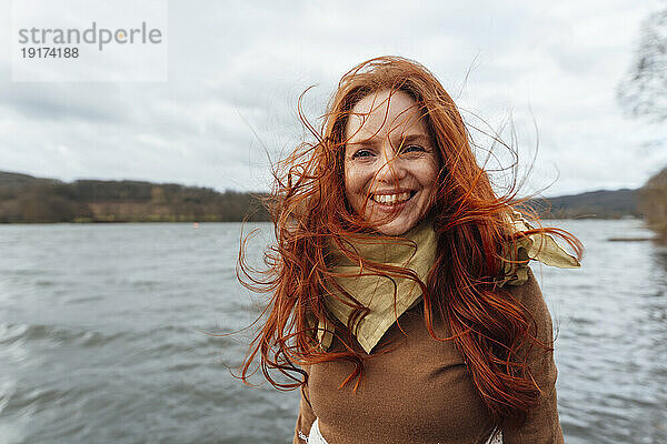 Glückliche rothaarige Frau mit im Wind wehenden Haaren