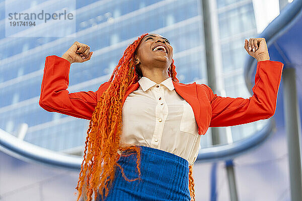 Lächelnde Geschäftsfrau feiert Erfolg im Büropark