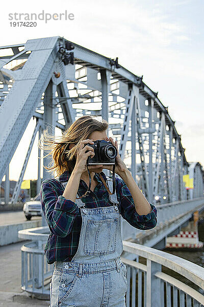 Frau fotografiert mit der Kamera an der Brücke