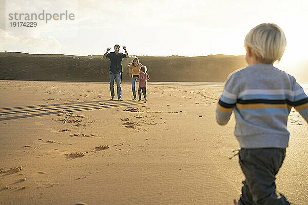 Glückliche Familie  die zusammen am Strand spielt
