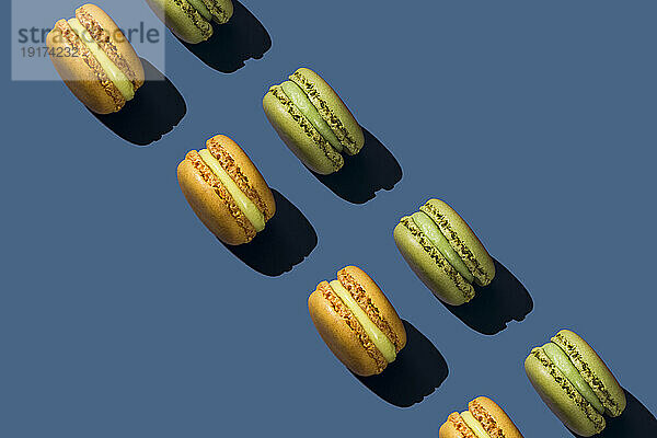 Green and yellow macaroons arranged on blue background