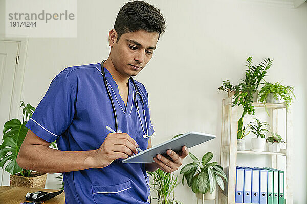 Junger Arzt arbeitet an einem Tablet-PC in einer medizinischen Klinik