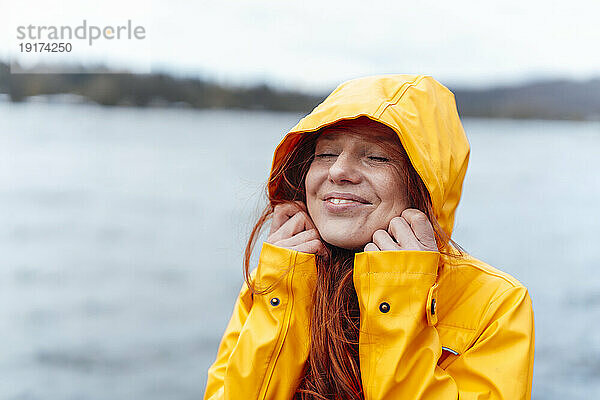 Smiling woman with eyes closed wearing hood of jacket