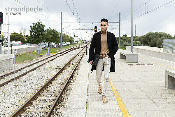 Young man walking on railroad station platform