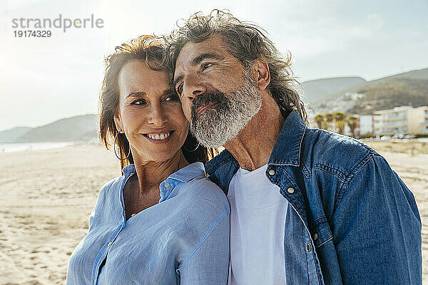 Thoughtful senior man with smiling woman at beach on weekend