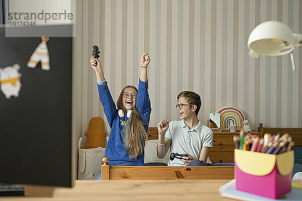 Fröhliches Mädchen feiert zu Hause mit Freund das siegreiche Videospiel