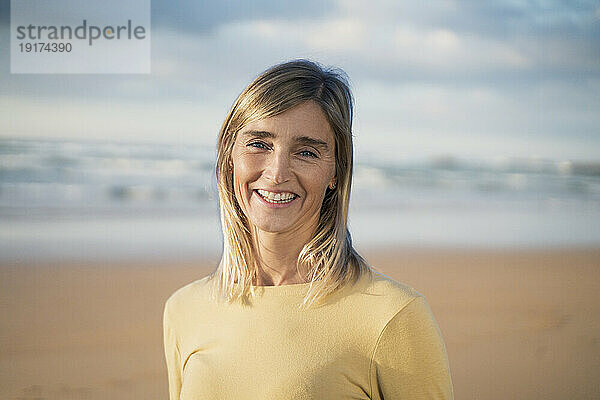 Lächelnde blonde Frau am Strand