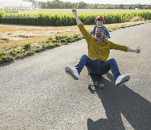 Glücklicher Mann genießt Skateboarden und Enkel schubst ihn von hinten